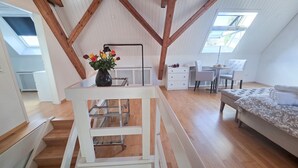 Amplia habitación en el ático con cama elevada, escritorio y silla.