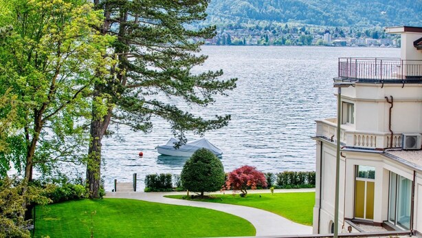 Una propiedad junto al lago con un césped cuidado, un pequeño jardín y vistas al lago.