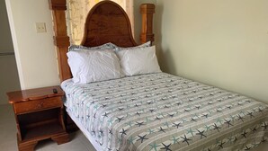 A neatly made bed with a star-patterned bedspread, a wooden headboard, and a nightstand with a drawer. - Charming 3-bedroom house with AC, WiFi in delightful Savanna La Mar (Savanna La Mar)