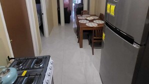 A kitchen with a gas stove, a refrigerator, a dining table with chairs, and a hallway leading to another room. - Charming 3-bedroom house with AC, WiFi in delightful Savanna La Mar (Savanna La Mar)