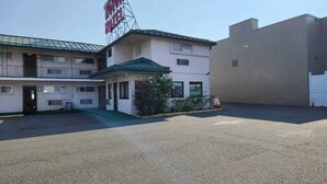Un motel con un letrero que dice "MOTOR HOTEL", una pequeña recepción y un estacionamiento.