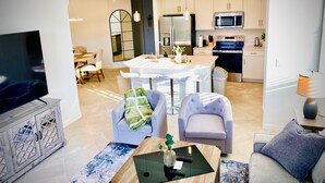 A modern living room with a TV, seating, and a dining area.