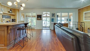 A spacious kitchen with a wooden bar, a leather couch, and a large window. - Repère tranquille au bord du lac (Saint-Alexis-des-Monts)