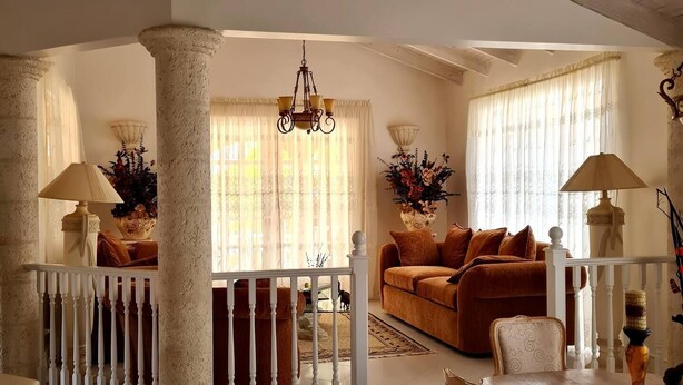 Uma sala de estar ampla com teto alto, um candelabro e um conjunto de sofás.