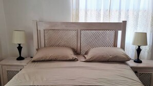 Uma cama bem arrumada com duas almofadas e duas luminárias de cabeceira em mesas de apoio combinando.