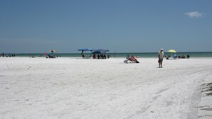 A beach with umbrellas, people, and a clear sky.