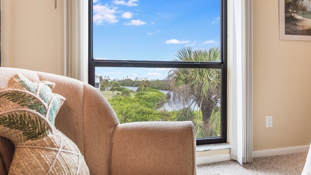 A living room with a large window overlooking a lake and greenery.