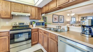 A modern kitchen with wooden cabinets, stainless steel appliances, and a large island with a sink.