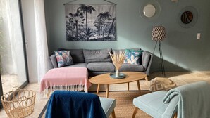 Un salón con un sofá gris, una mesa de centro, un sillón azul y una lámpara de pie.