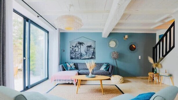 Una sala de estar moderna con un sofá, dos sillones, una mesa de centro y un ventanal grande.