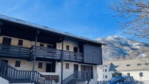 A building with a staircase leading to a balcony, a sign indicating a ski resort, and a car parked in front.