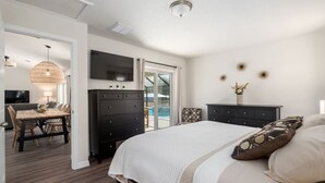 Un dormitorio con una cama grande, un aparador, un televisor y un rincón comedor con una mesa y sillas.