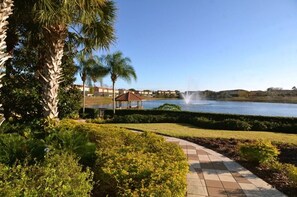 A landscaped area with a water feature, palm trees, and a gazebo. - Lovely 3 Bed Townhome in Encantada Resort-3036SLD (Kissimmee)