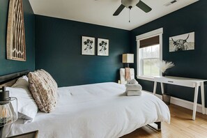 A bedroom with a bed, bedside lamp, and artwork on the wall.