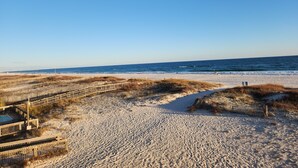 Ein sandiger Strand mit Holzstegen und blauem, wolkenlosem Himmel.