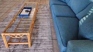 Ein modernes Wohnzimmer mit einem blauen Sofa, einem Couchtisch und einem Essbereich mit einer Pendelleuchte.