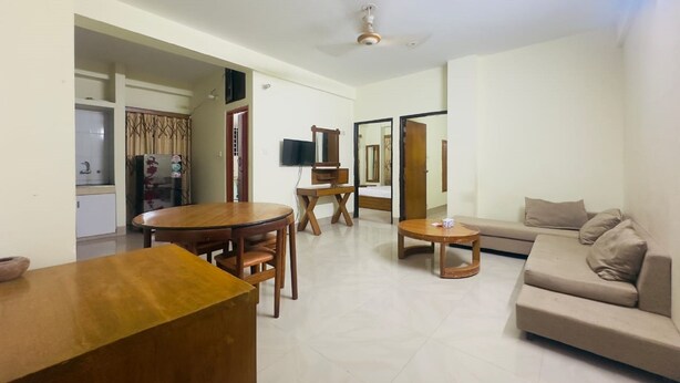 A spacious living area with a sofa, a dining table, and a TV.