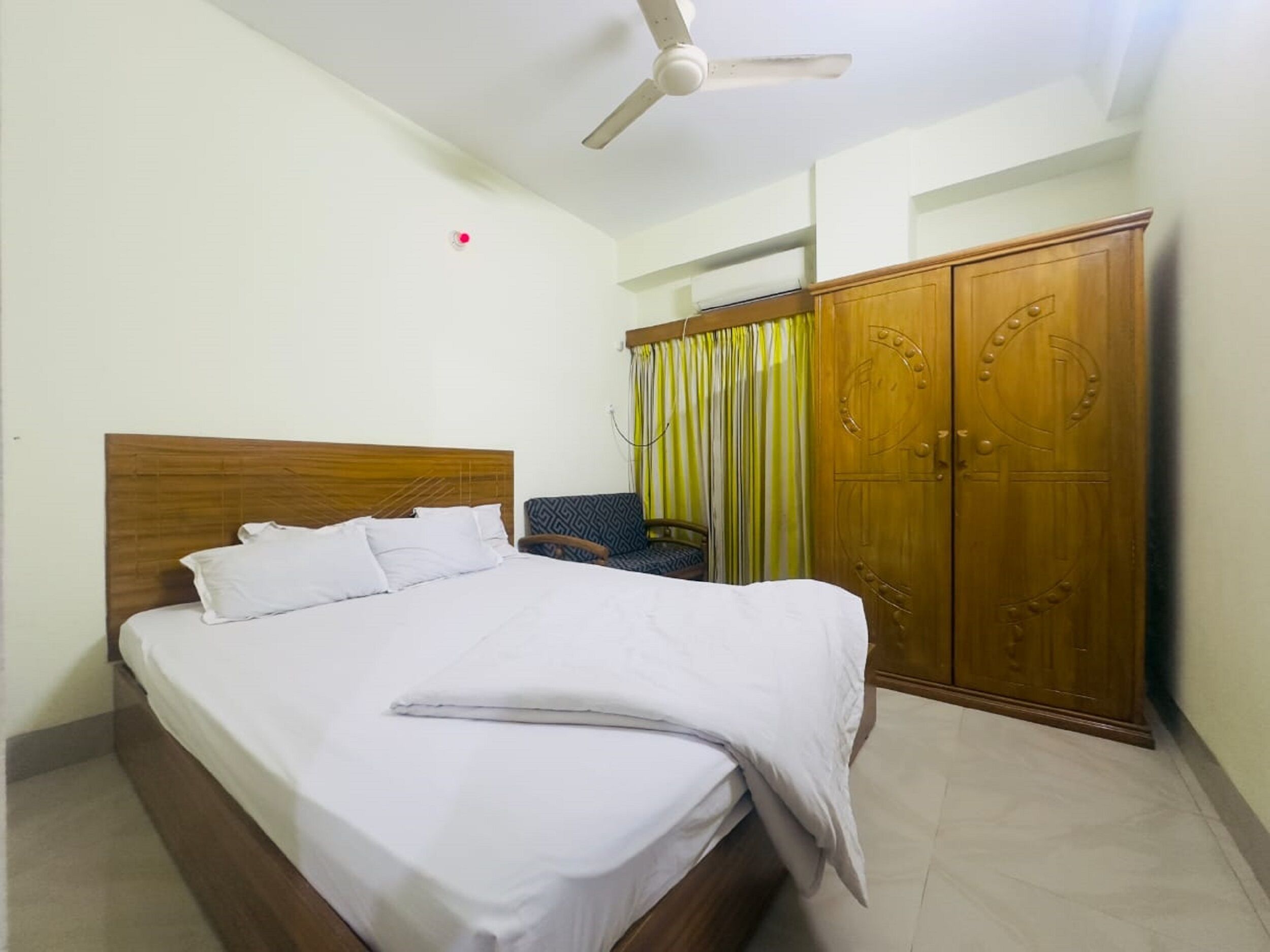 A neatly made bed with white linens, a wooden headboard, and a ceiling fan.