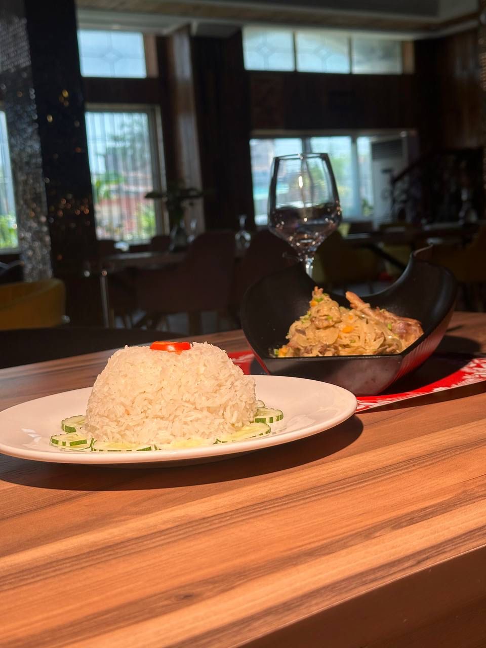 A dining table with a plate of white rice and a bowl of fried rice.