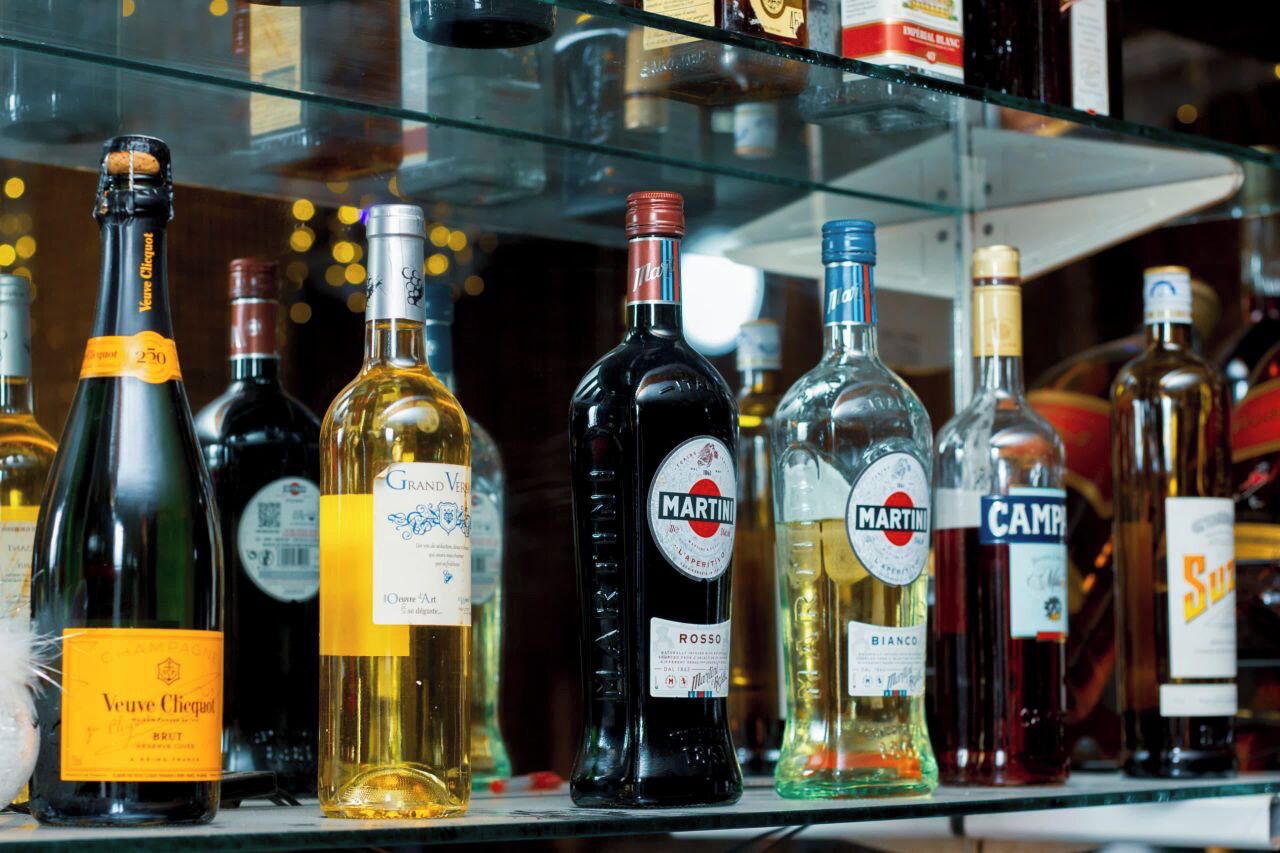 A variety of liquor bottles on a glass shelf.