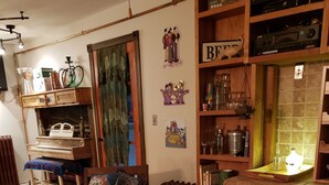 Een gezellige woonkamer met een piano, een blauwe bank en een houten boekenkast vol diverse objecten.