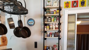 Een keuken met een fornuis, hangende pannen, een rek voor kruiden en een decoratieve wand met schilderingen van schildpadden.