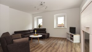 Una sala de estar moderna con un sofá modular, una mesa de centro redonda y un mueble para televisión.
