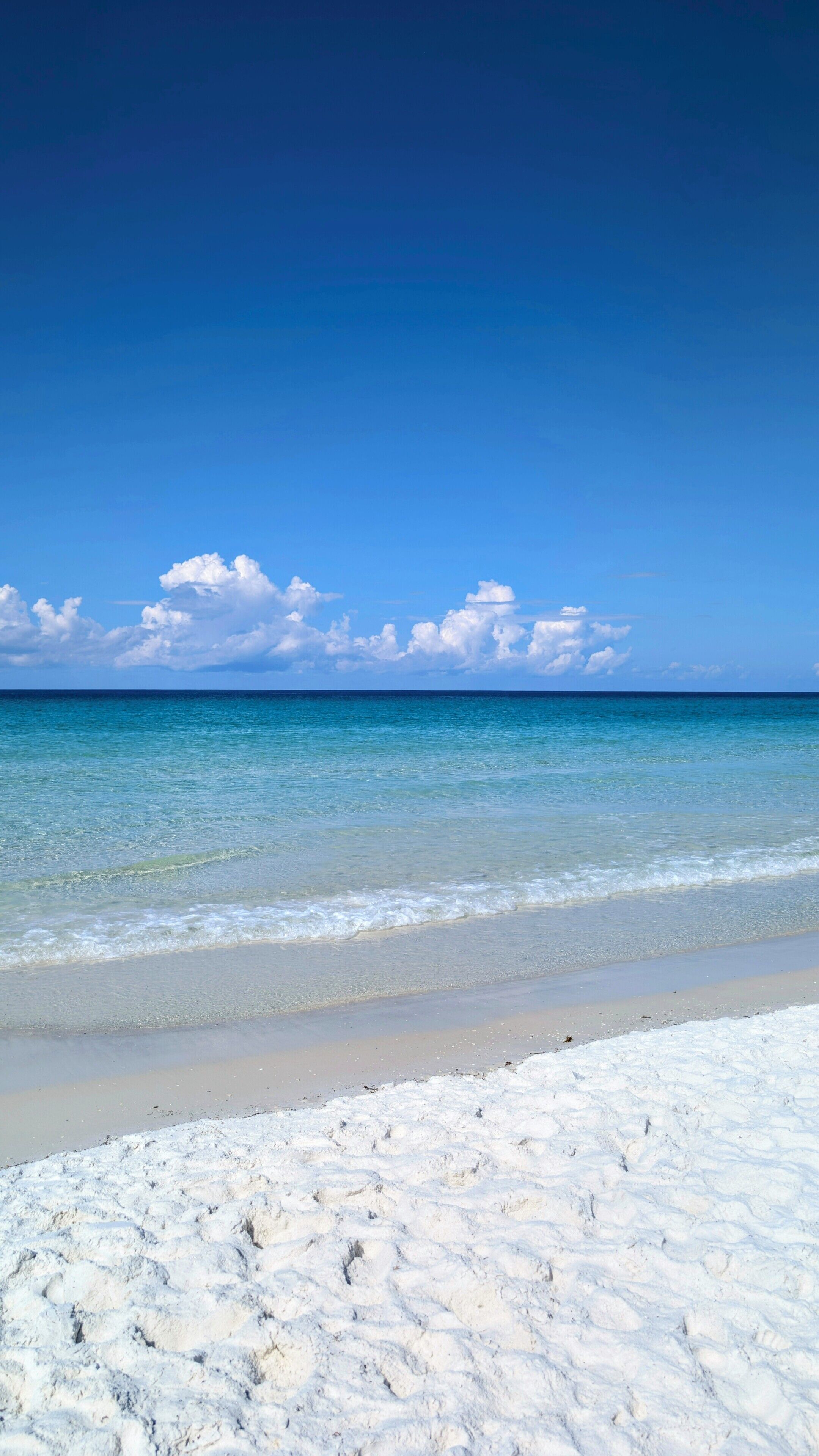 A beach with clear blue water and white sand.