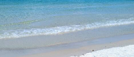 A beach with clear blue water and white sand.
