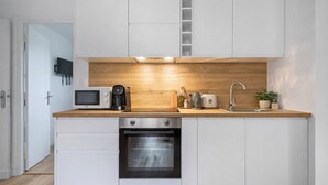 A compact kitchen with white cabinets, a wooden countertop, a built-in oven, and a microwave.