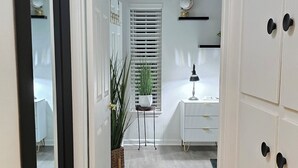 A hallway with a white door leading to a room with a desk and a globe on a shelf.