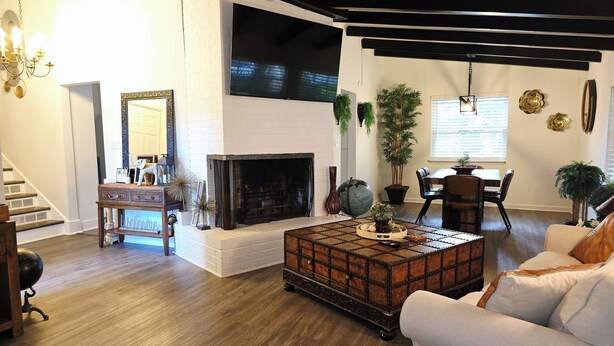 A living room with a fireplace, wooden flooring, a white sofa, a coffee table, and a staircase.