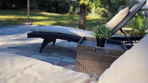 A lounge area with a wicker chair, a small potted plant, and a thatched umbrella.