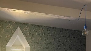 Ein Schlafzimmer mit einem Bett, einem kleinen weißen Stuhl, einem Fenster und einer Wand mit Muster.