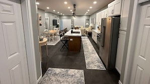 Una cocina moderna con gabinetes blancos, una isla central y un comedor con sillas y una mesa.