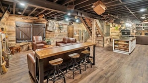 Eine rustikale Bar mit Holzboden, Ledersitzhocker und einer Holztresen.