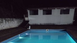 Una piscina rettangolare con fondo piastrellato e bordo in pietra.