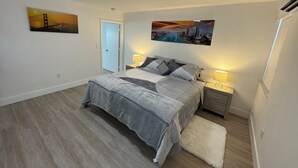 Una camera da letto con un letto, due comodini, una porta e due quadri appesi al muro.