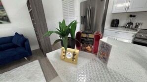 Una cucina moderna con elettrodomestici in acciaio inossidabile, un divano blu e una pianta decorativa.