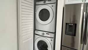 Una lavanderia con due lavatrici affiancate e un frigorifero in acciaio inox.
