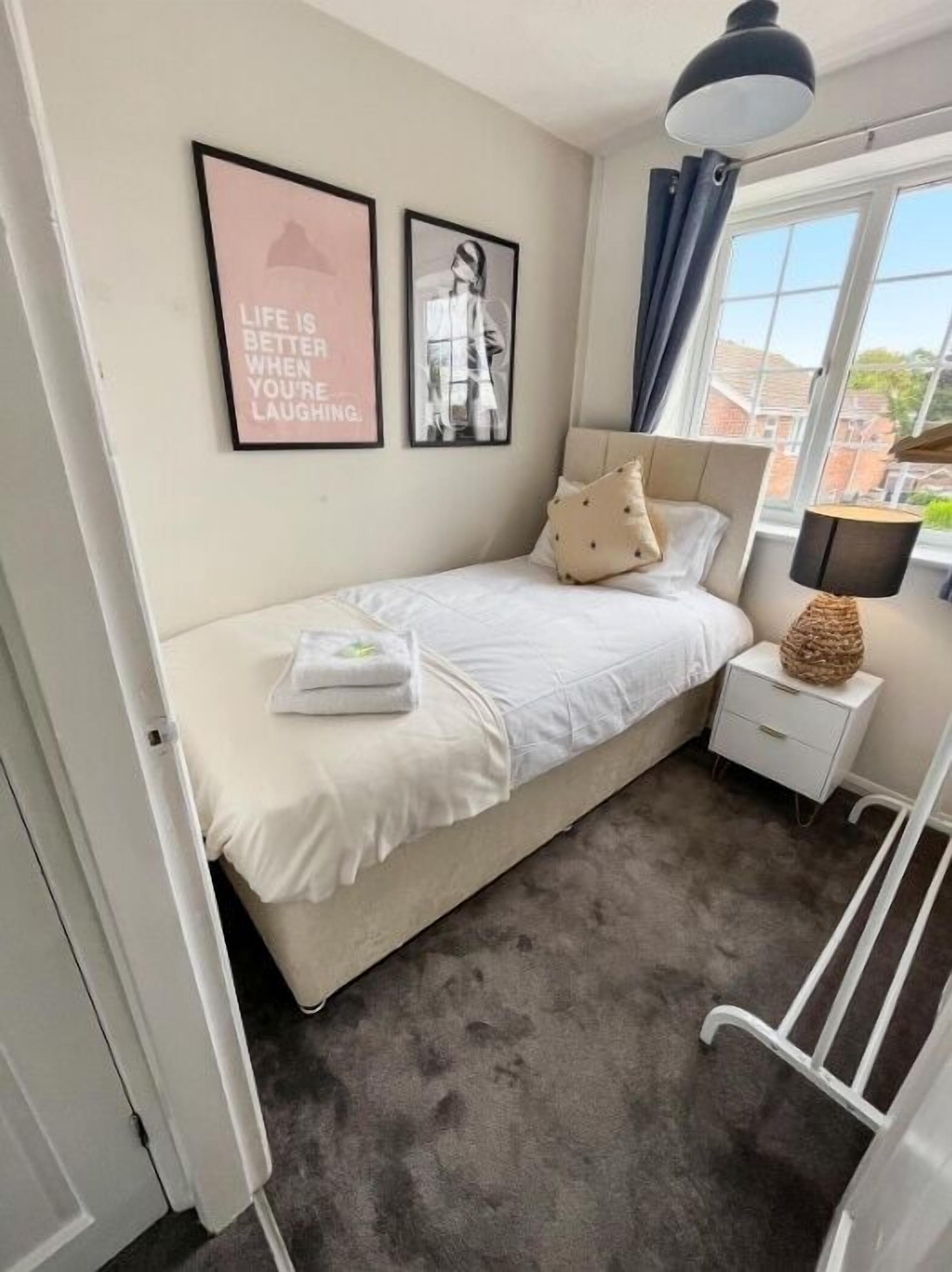 A bedroom with a bed, a nightstand, a lamp, and two framed pictures on the wall.