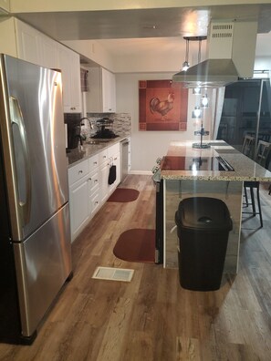 Een moderne keuken met roestvrijstalen apparatuur, een centraal eiland en een eetgedeelte met uitzicht.