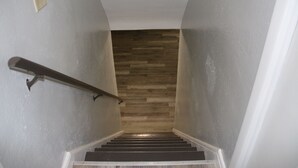 Un escalier avec une finition en bois sur le dessus, des murs blancs et une main courante en métal.
