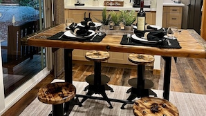 Een eetgedeelte met een houten tafel voor vier personen, een bord met daarop 'coffee bar' en een keuken op de achtergrond.