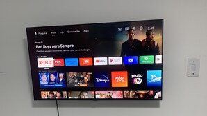 Un televisore fissato al muro mostra l'interfaccia di un servizio di streaming con diverse icone di applicazioni.