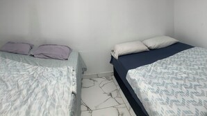 Una camera da letto con due letti, ognuno con una diversa coperta a motivi.