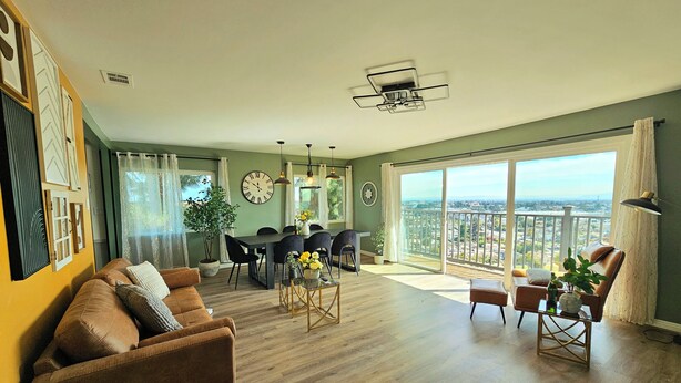 A spacious living area with a dining table, chairs, a sofa, and a balcony with a city view. - Ideally located, easy access, & stunning city views! with king size bed. (Alhambra)