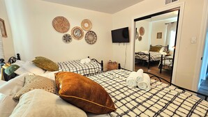 A bedroom with a bed, pillows, a flat-screen TV, and decorative wall hangings. - Ideally located, easy access, & stunning city views! with king size bed. (Alhambra)