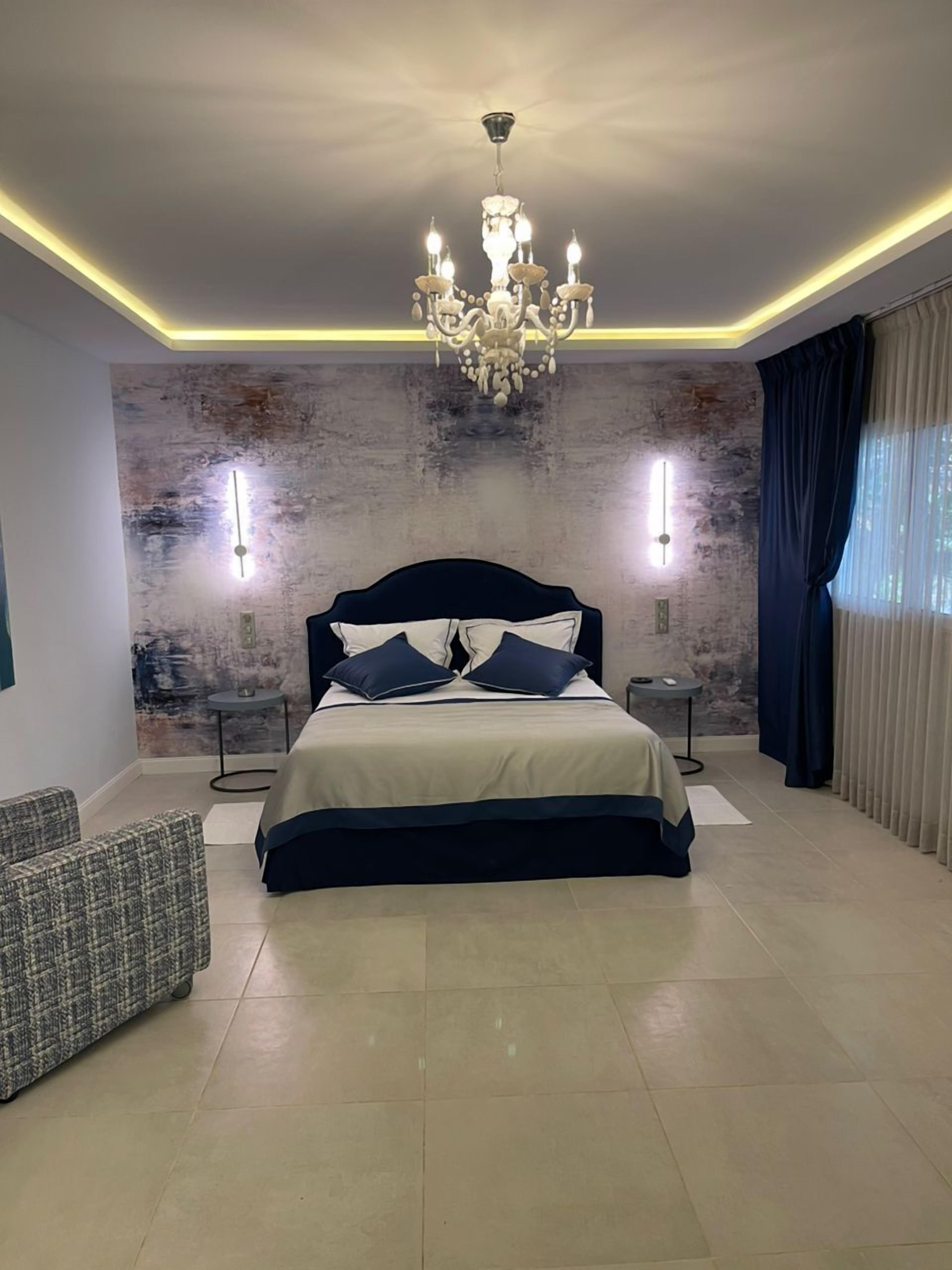 Un dormitorio moderno con una cama grande, una araña y dos lámparas de pared.