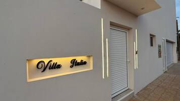 Una villa moderna con un cartel que dice "Villa Italia" y una puerta con persiana cerrada.